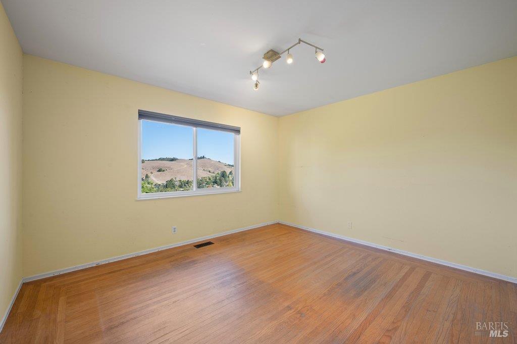 Empty room with hardwood floors and a window overlooking dry hills.