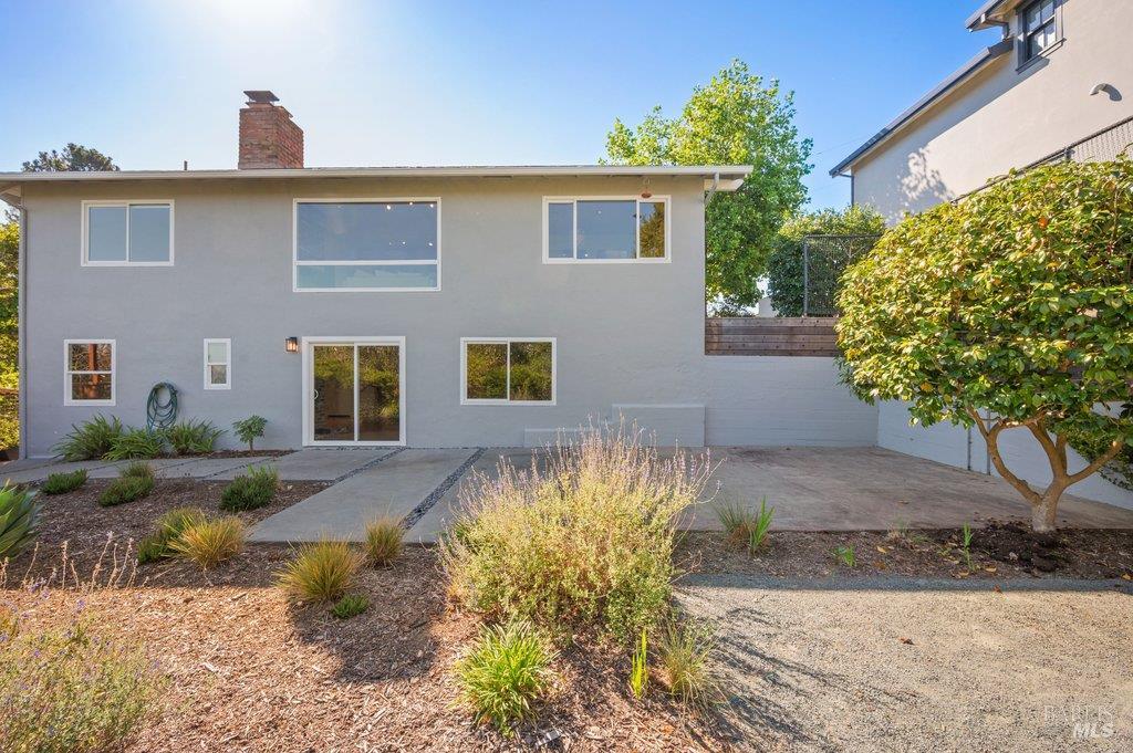 Rear of a gray two-story home with a paved patio and drought-tolerant landscaping.