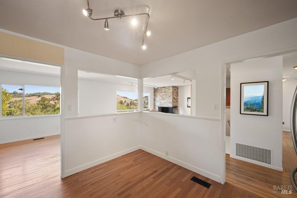 Interior room with hardwood floors, wide pass-through openings, and views of wooded hills.