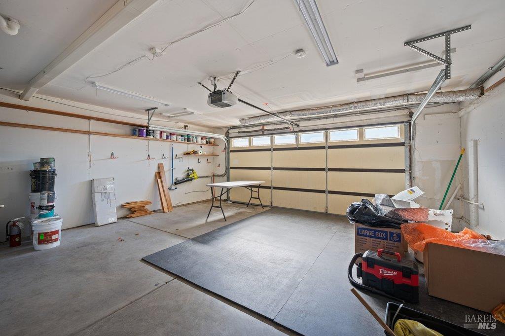 Garage with a closed windowed door, wall shelves, and stored boxes and tools.