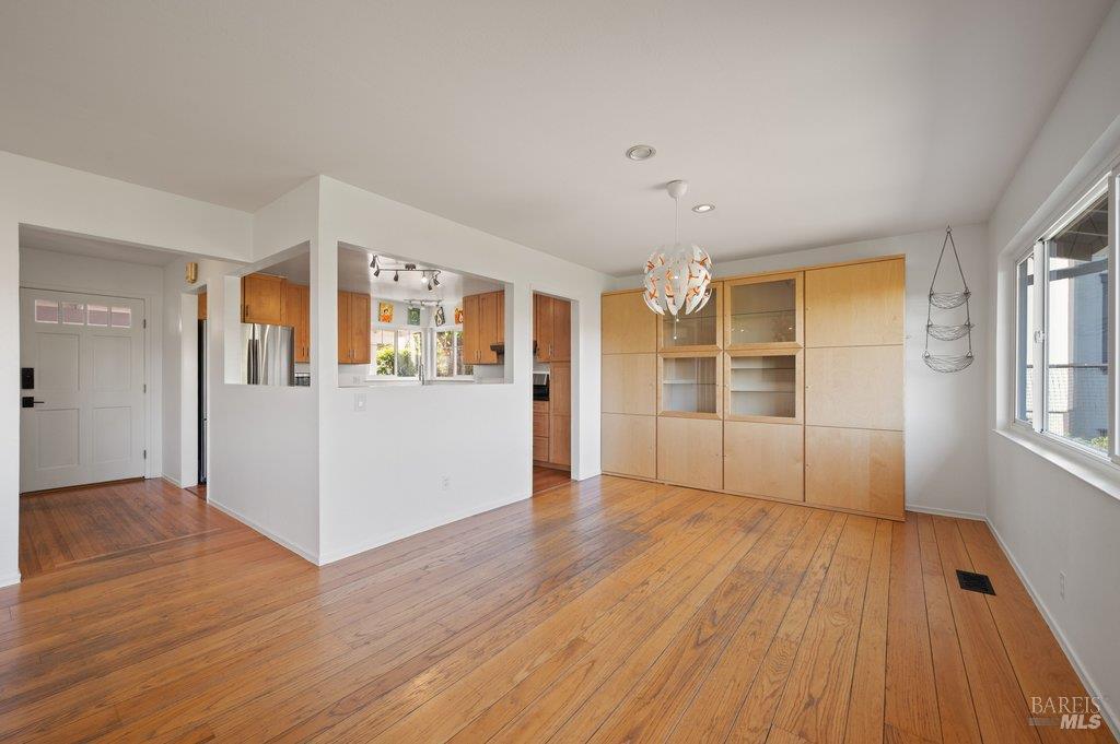 Unfurnished dining area with hardwood floors, built-in wood cabinetry, and a pendant light.