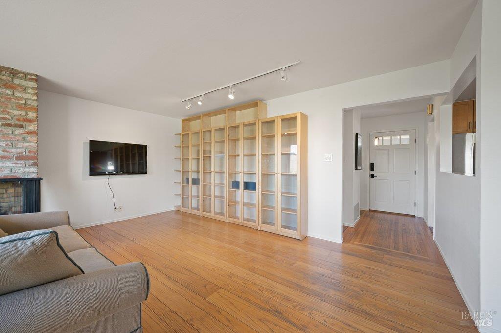 Living room with built-in wood shelving, hardwood floors, and a brick fireplace.