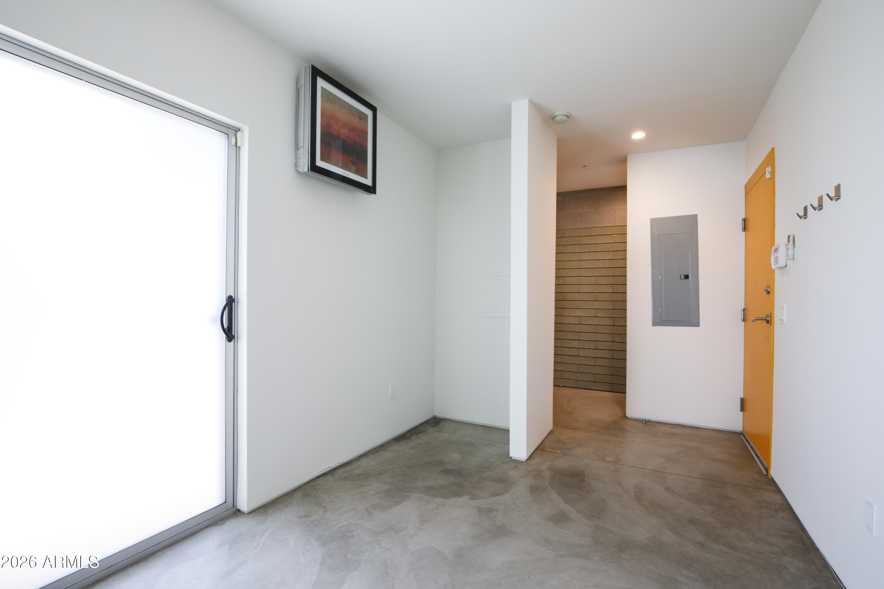 Apartment entry with concrete flooring, a frosted-glass sliding door, and an ochre-colored front door.