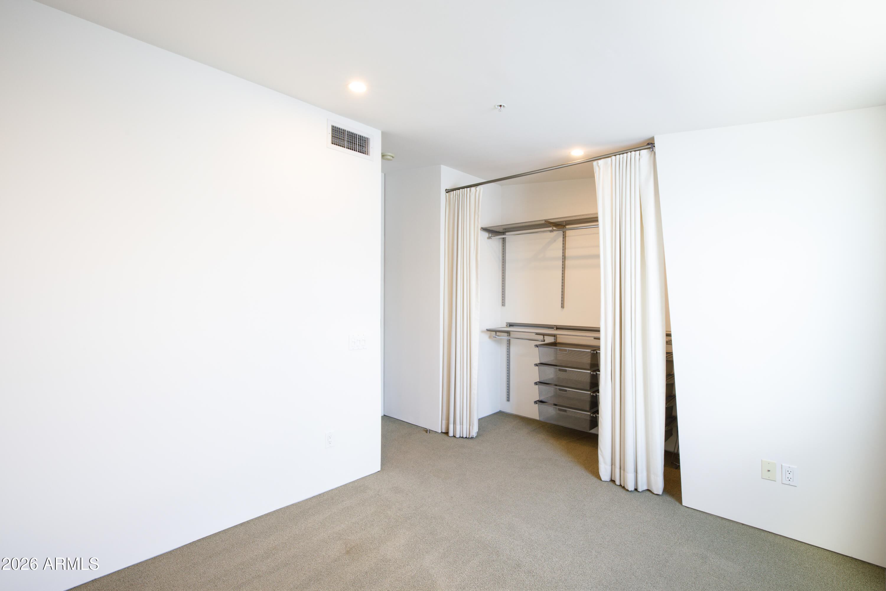 Walk-in closet with white curtains, metal shelving, and pull-out wire baskets.