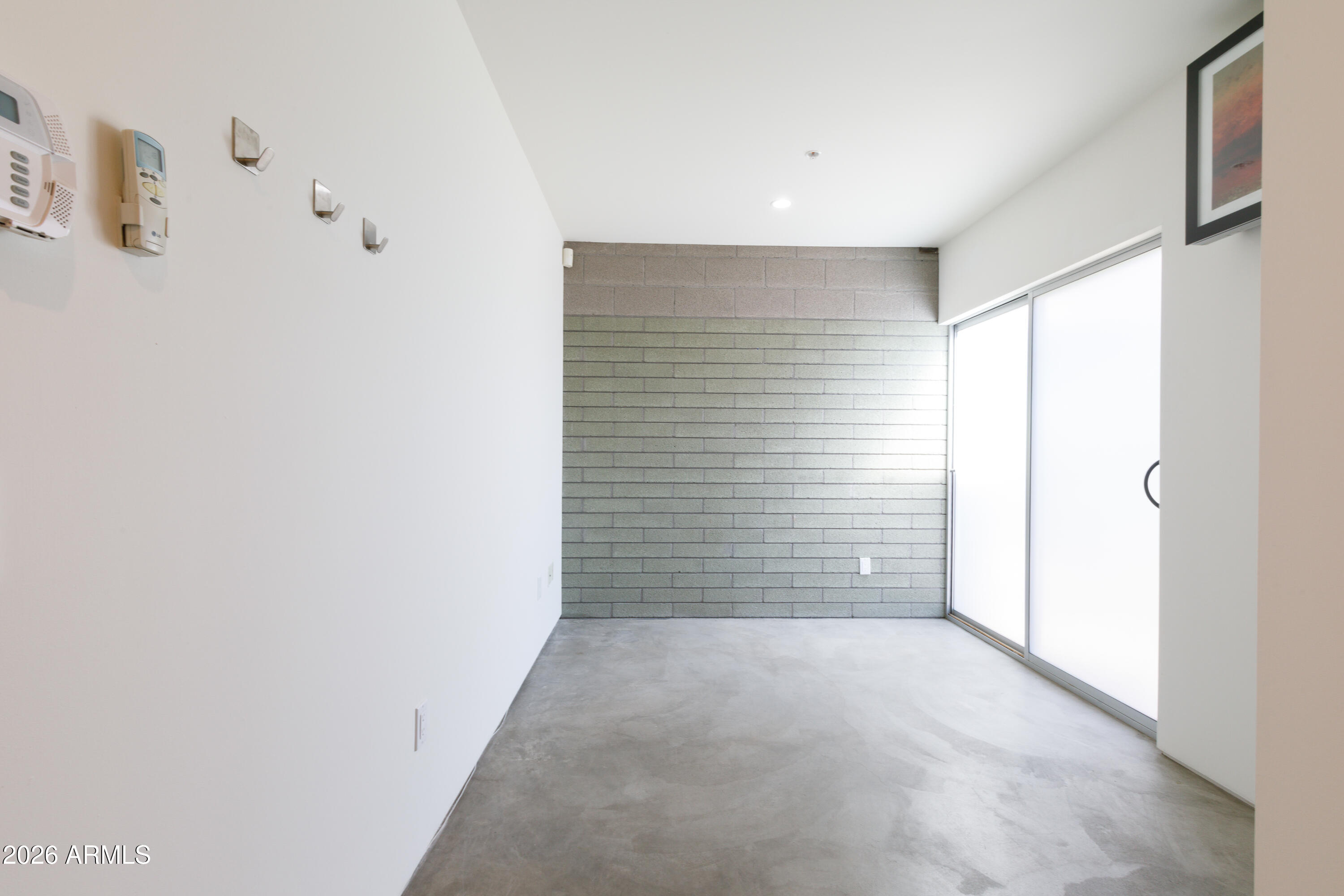 Vacant room with concrete floors, a gray block wall, and a large sliding glass door.