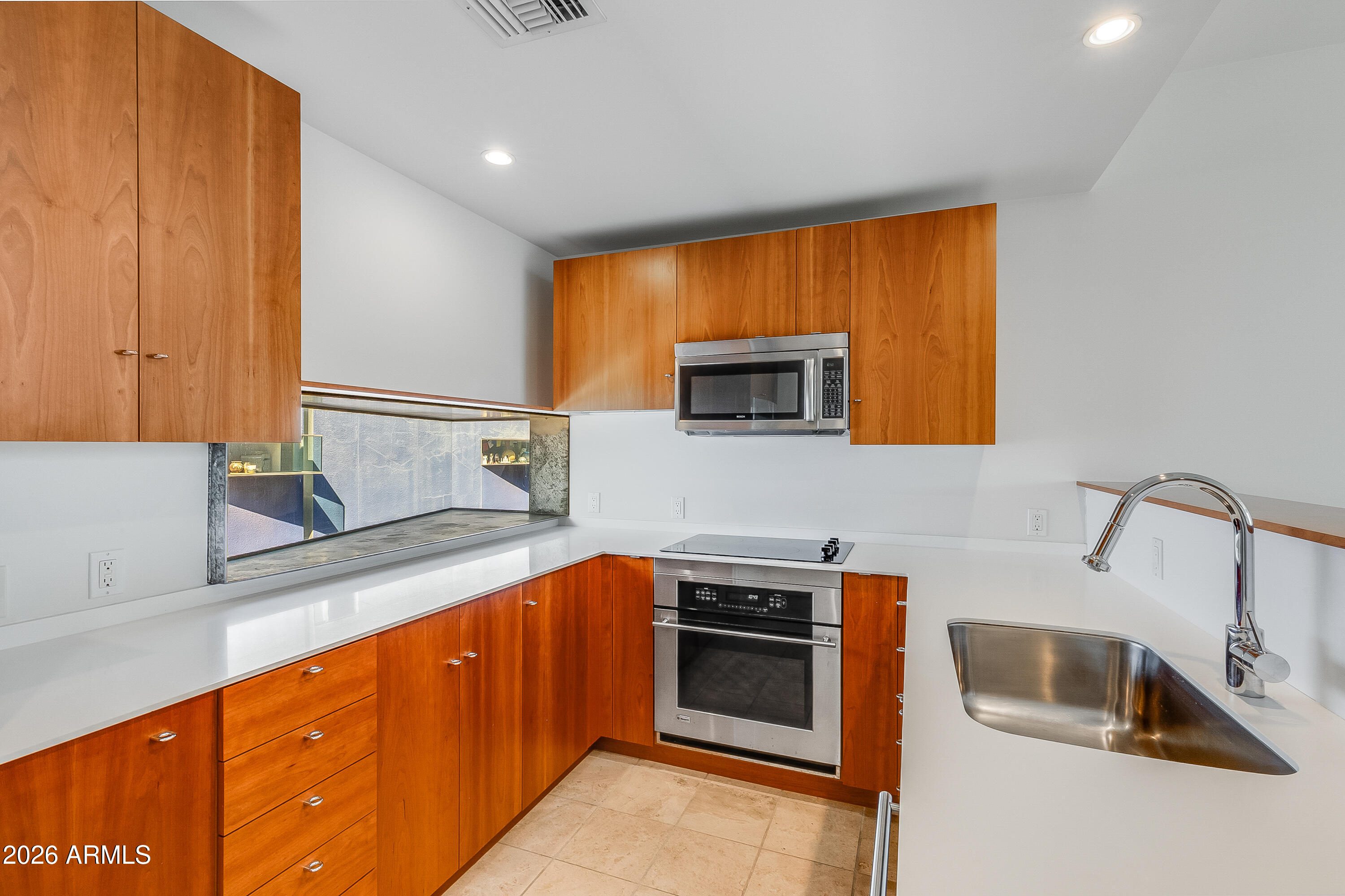 Kitchen with warm wood cabinets, white counters, stainless appliances, and a large sink.