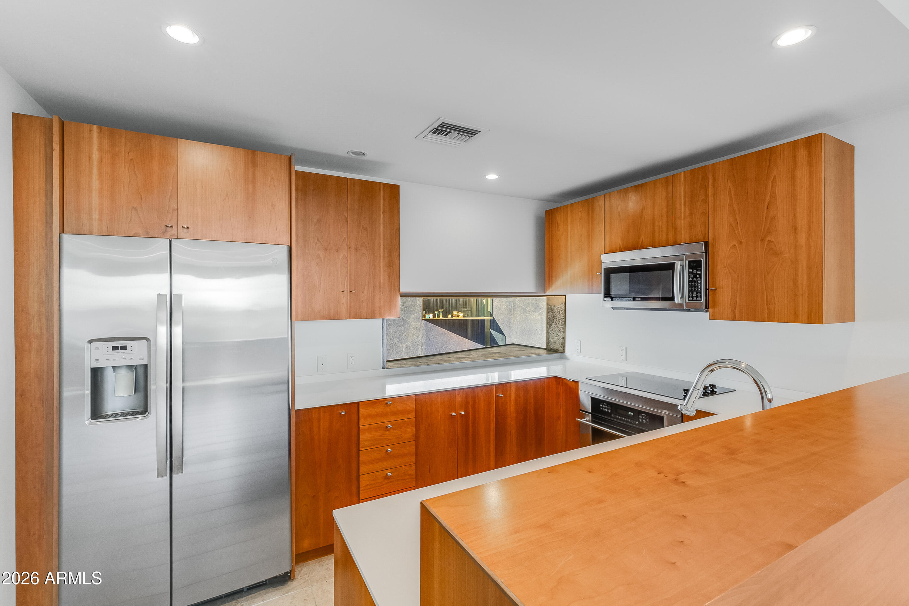Kitchen with warm wood cabinetry, stainless steel appliances, and a large wood-topped island.