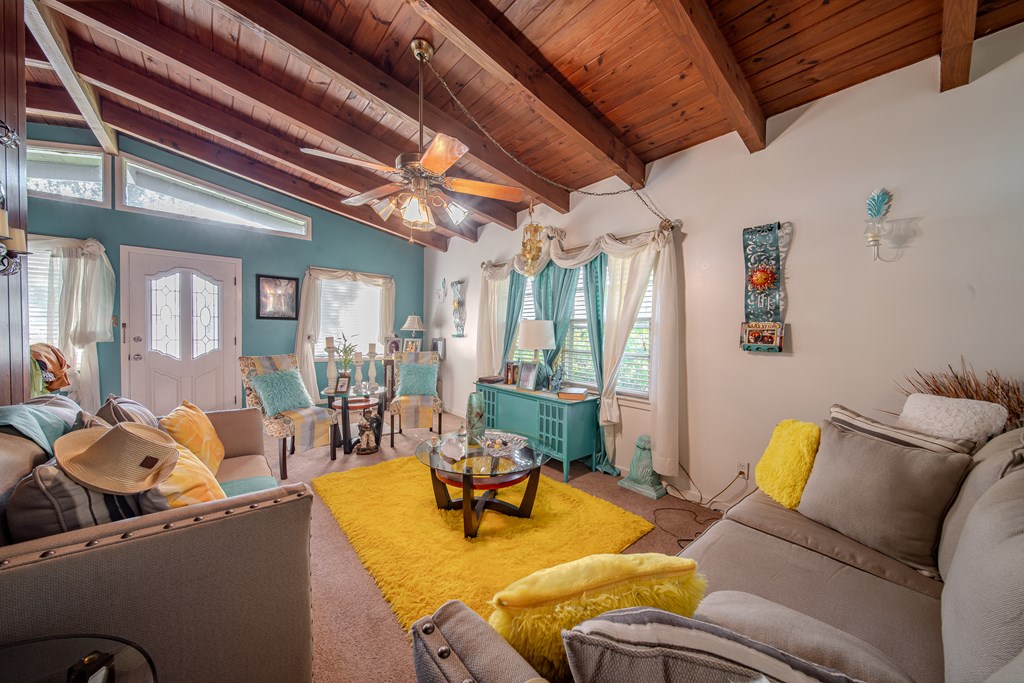 Living room with a vaulted wood ceiling, exposed beams, and teal accent wall.