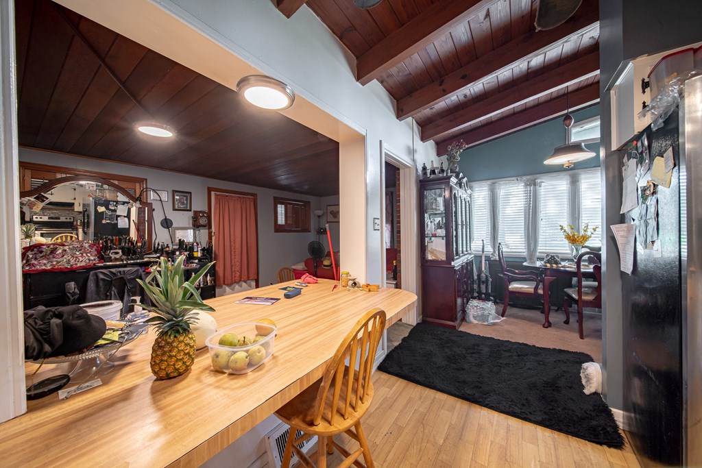 Kitchen and dining area with a long wood island, exposed wood ceilings, and a window-side dining nook.