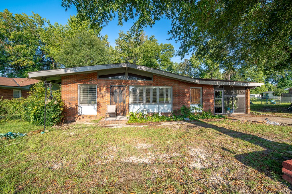 Single-story brick house with a broad low roof, large windows, and an enclosed screened area.