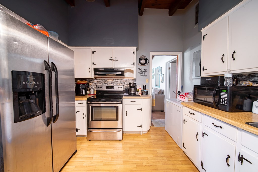 Kitchen with white cabinets, butcher-block counters, and stainless steel appliances.