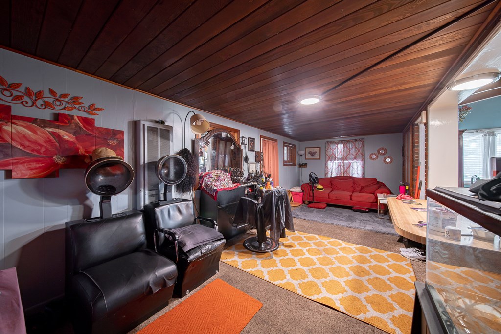 Salon-style room with styling chairs, a red sofa, and a wood-paneled ceiling.