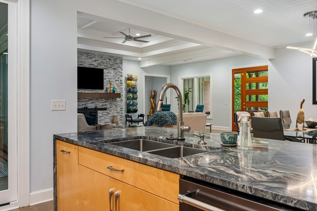 Kitchen island with dark stone counters and sink overlooking open living and dining areas.