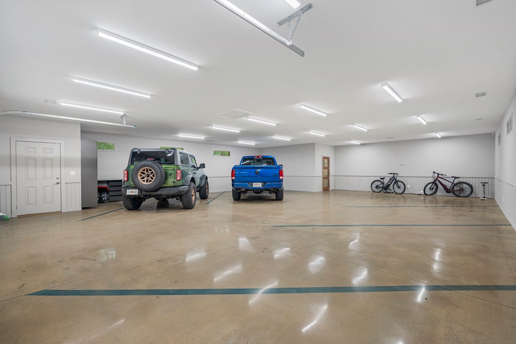 Spacious garage with polished concrete floors, two vehicles, and bicycles along the back wall.