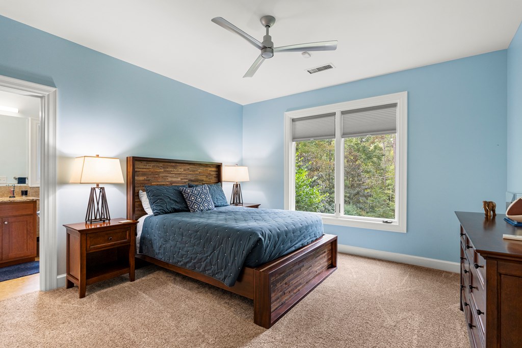 Bedroom with a dark wood bed, blue walls, and a large window overlooking trees.