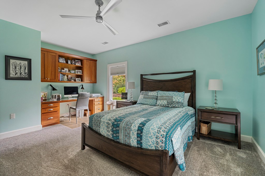 Bedroom with teal patterned bedding, aqua walls, and a built-in desk and shelves.
