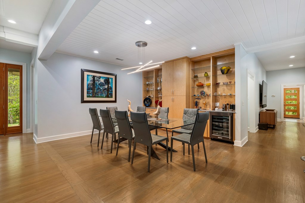 Dining room with a glass-top table, dark chairs, and built-in display cabinets.