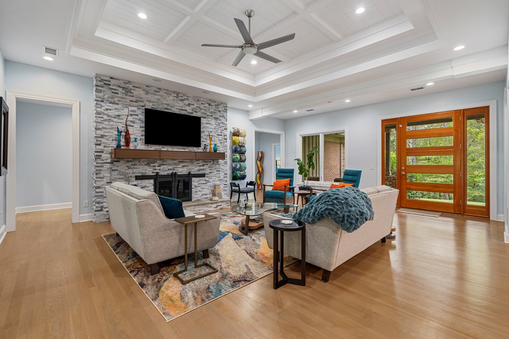 Living room with a stone fireplace wall, vaulted ceiling, and wood-framed glass doors.