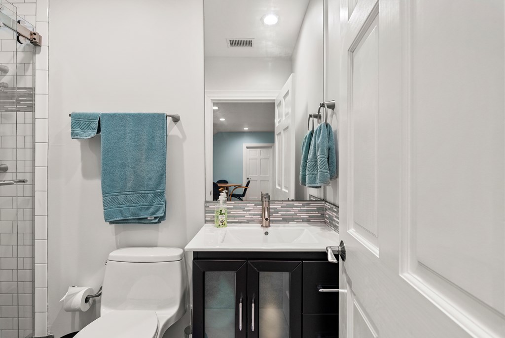 Bathroom with a tiled shower, dark vanity, and blue towels.