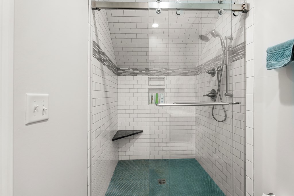 Walk-in shower with white subway tile, a glass enclosure, and turquoise floor tile.