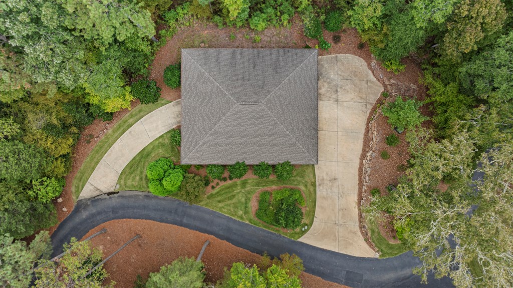Aerial view of a home with a curved driveway surrounded by mature trees.