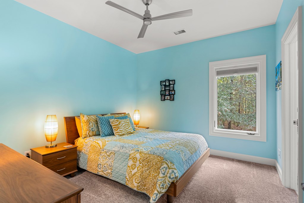 Bedroom with turquoise walls, a patterned quilt, and a window overlooking trees.