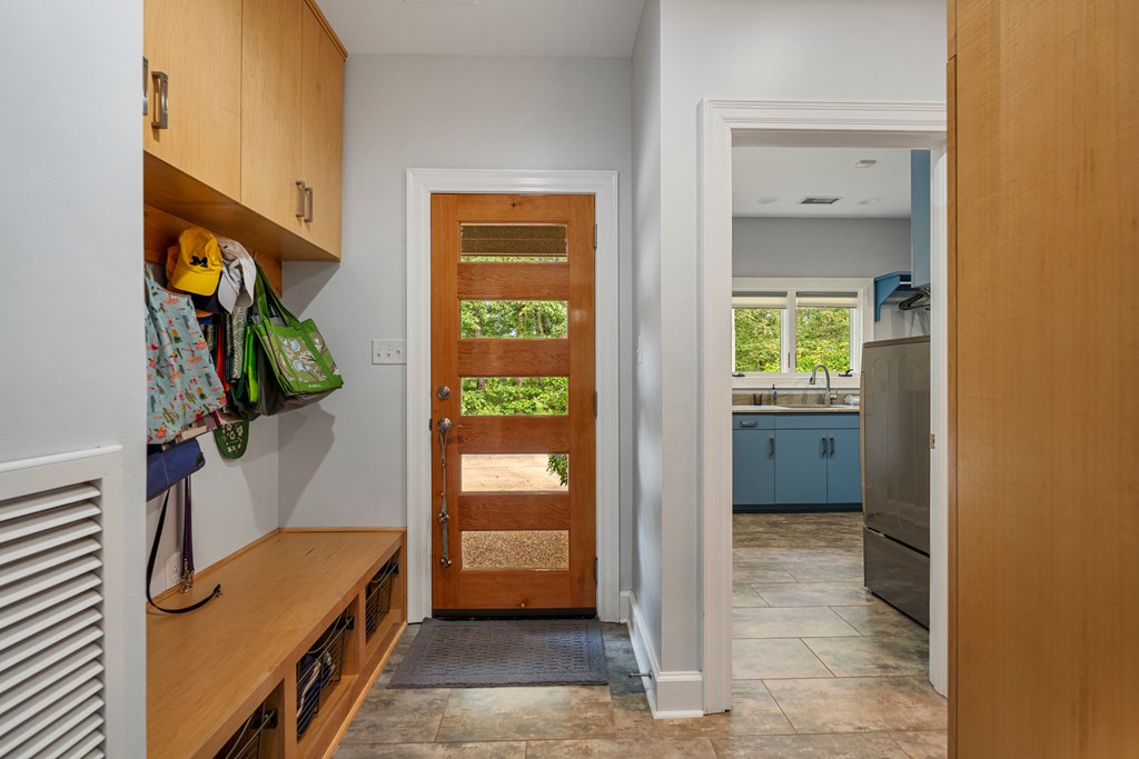 Mudroom with built-in wood storage bench and a glass-paneled wood entry door.