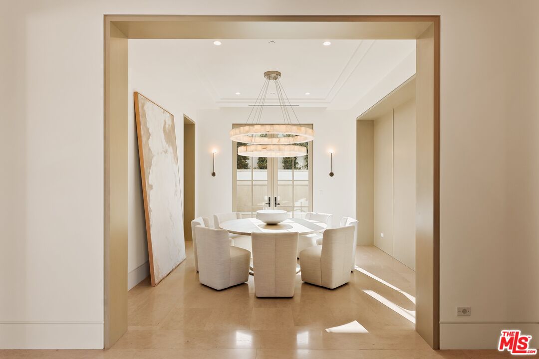 Contemporary dining room with a round table, sculptural chandelier, and oversized abstract artwork.