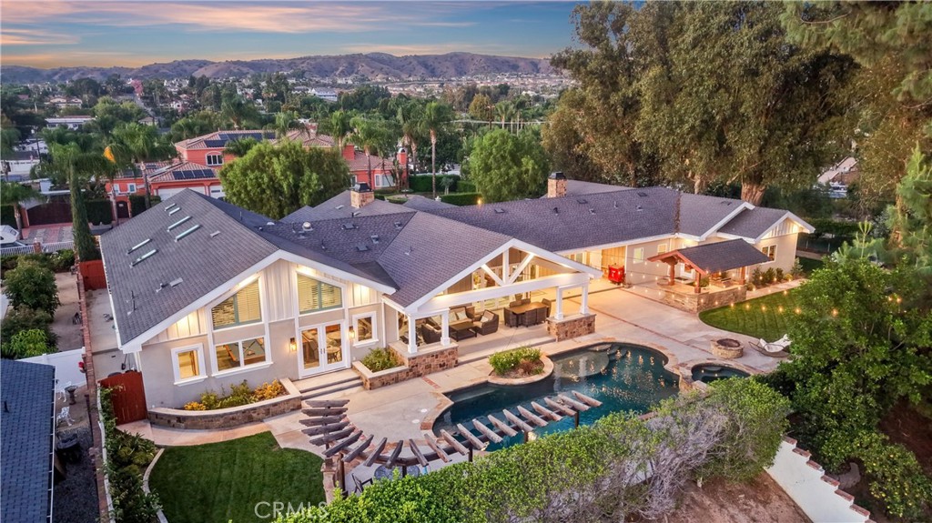 Large California home with a swimming pool and landscaped patio at sunset.