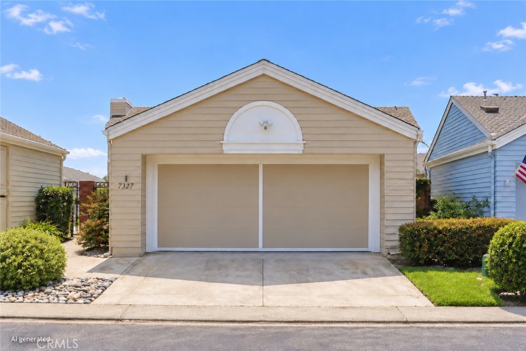 Beige detached garage with a wide double door and concrete driveway.