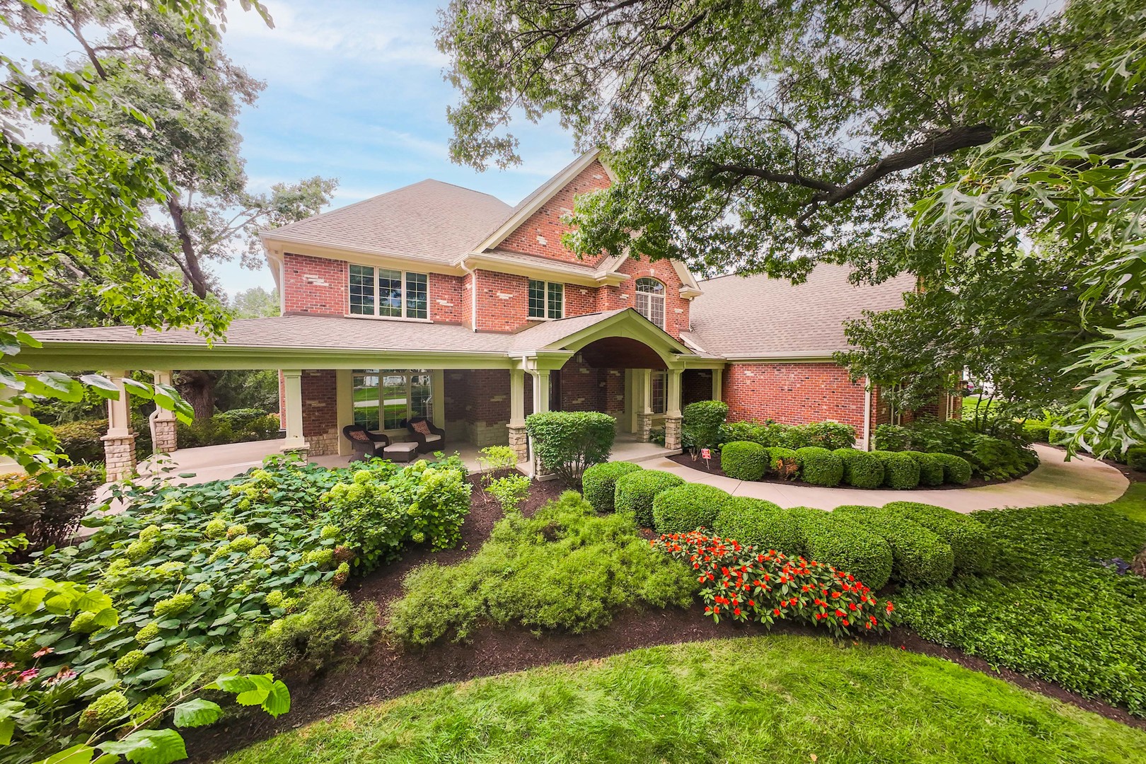 Two-story brick home with a covered porch, arched entry, and landscaped garden.
