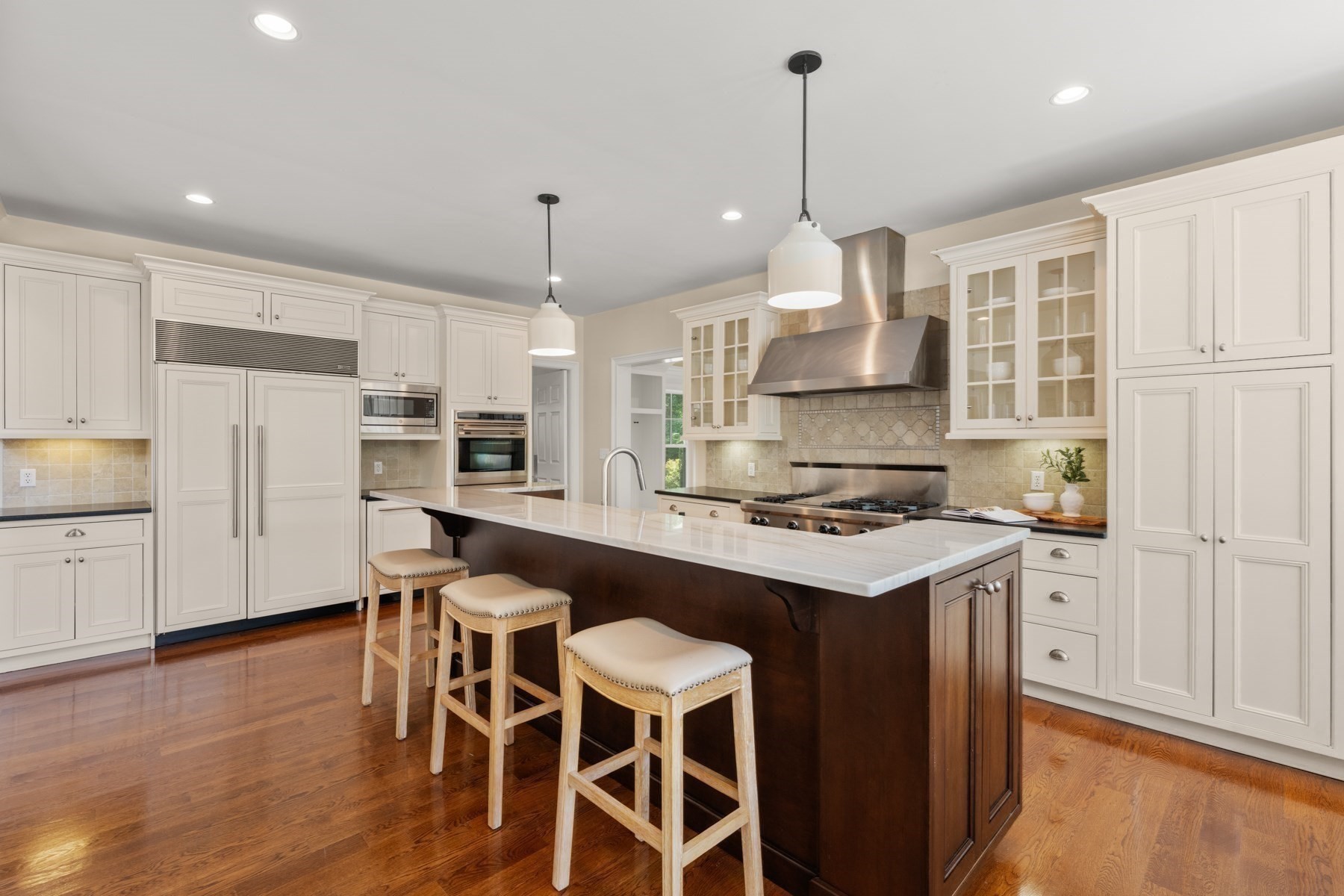Kitchen with a large dark-wood island, white cabinetry, stainless-steel appliances, and hardwood floors.