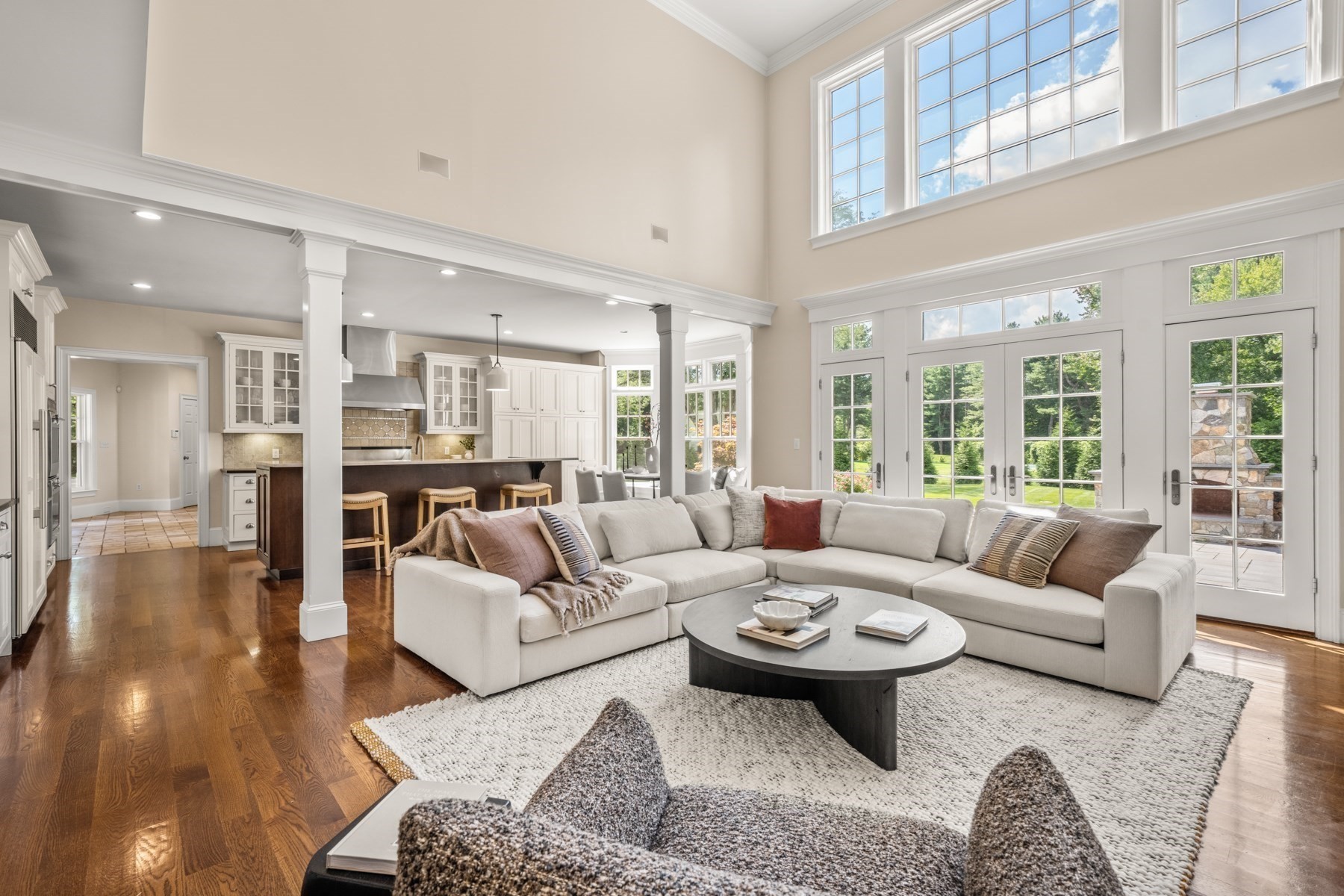 Open-plan living room with a white sectional, vaulted ceiling, and French doors to the yard.