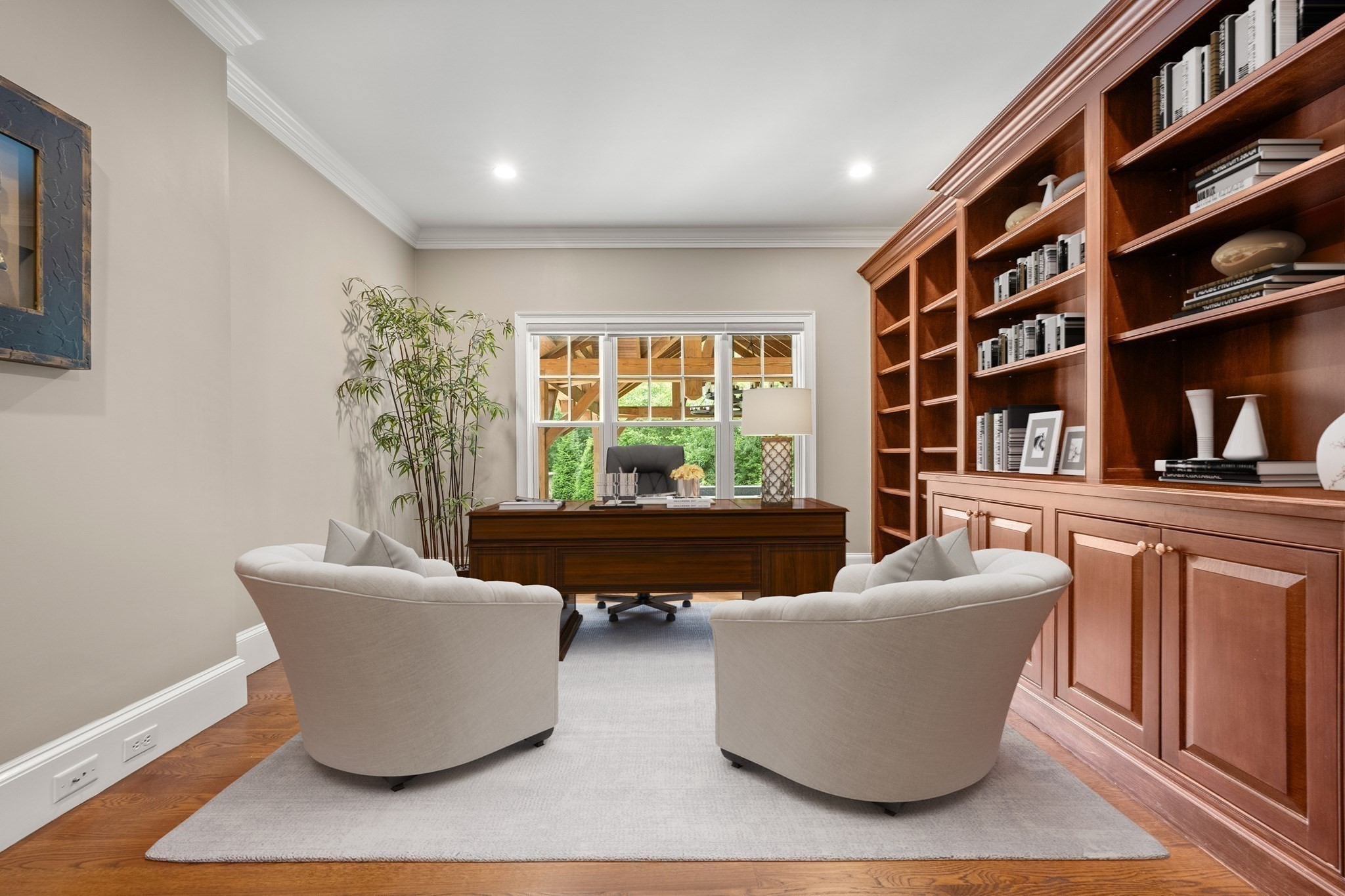 Furnished home office with built-in wood bookcases, a desk, and two cream chairs.