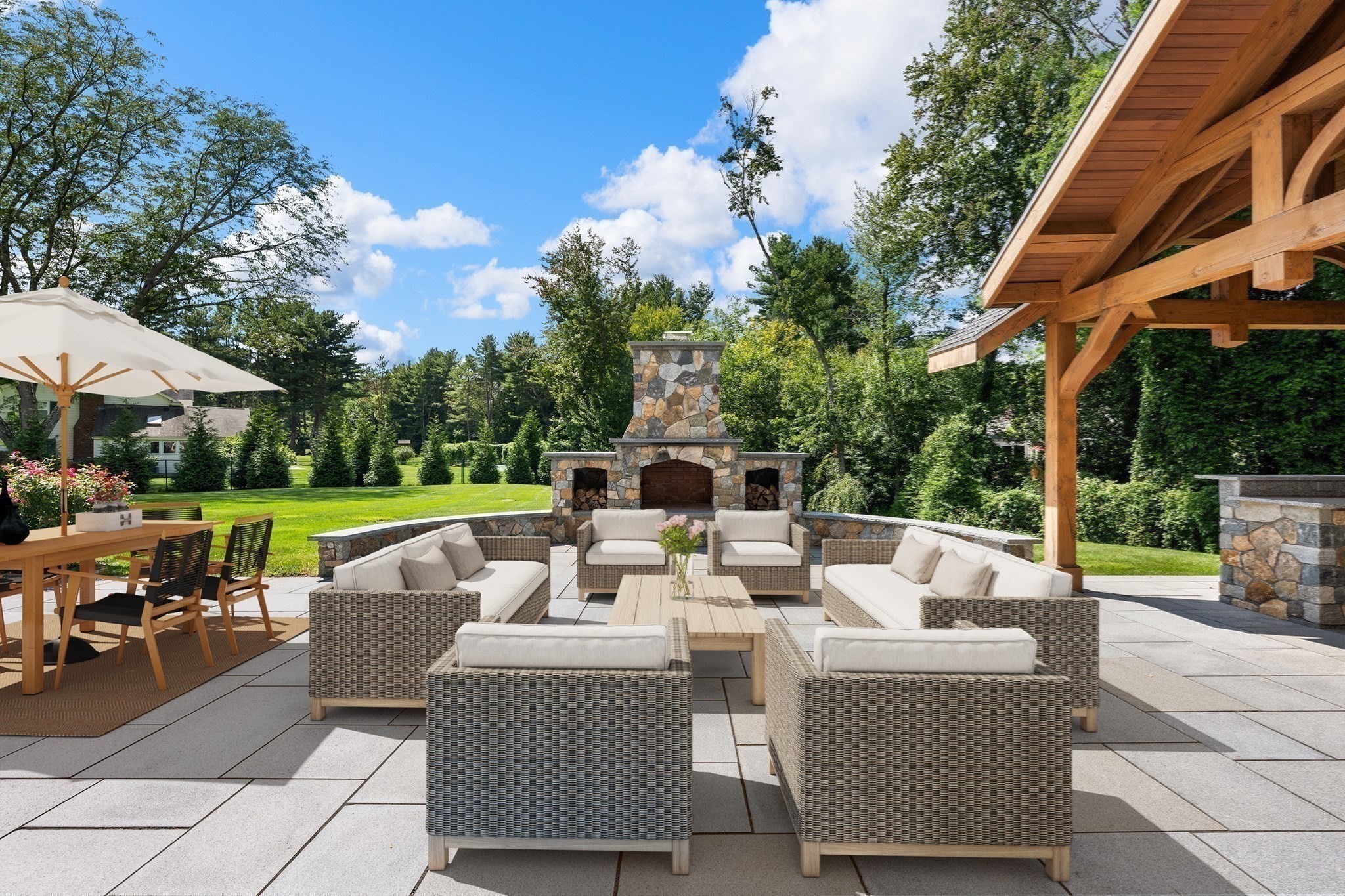 Outdoor patio with wicker lounge seating, a stone fireplace, and a timber pavilion.