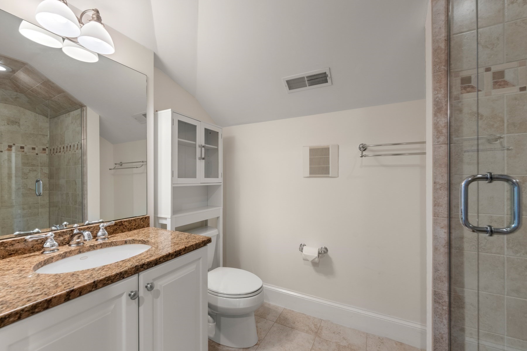 Bathroom with a granite vanity, white cabinetry, and a glass-enclosed tiled shower.