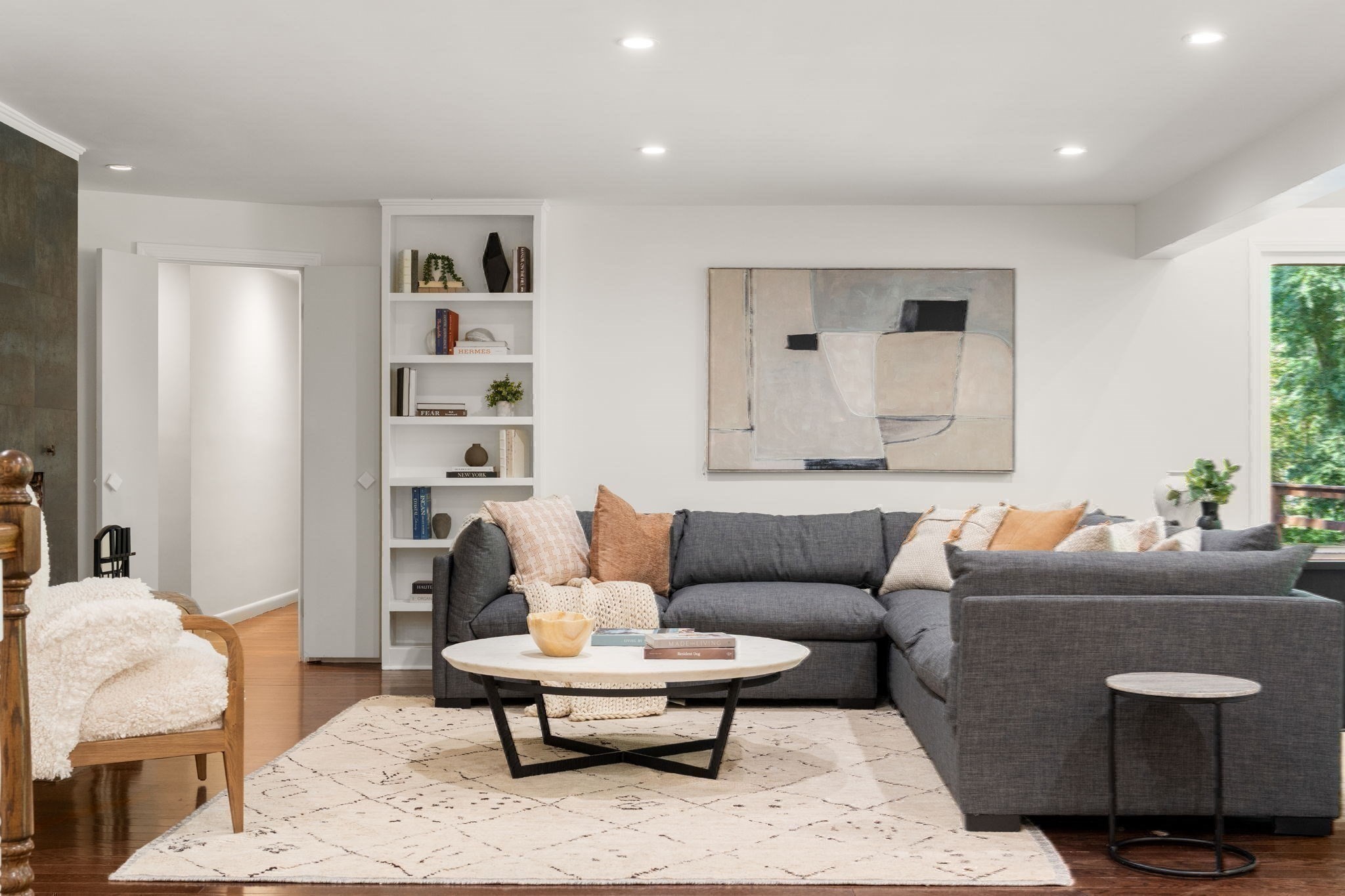 Living room with a charcoal sectional, built-in bookshelves, and abstract artwork.