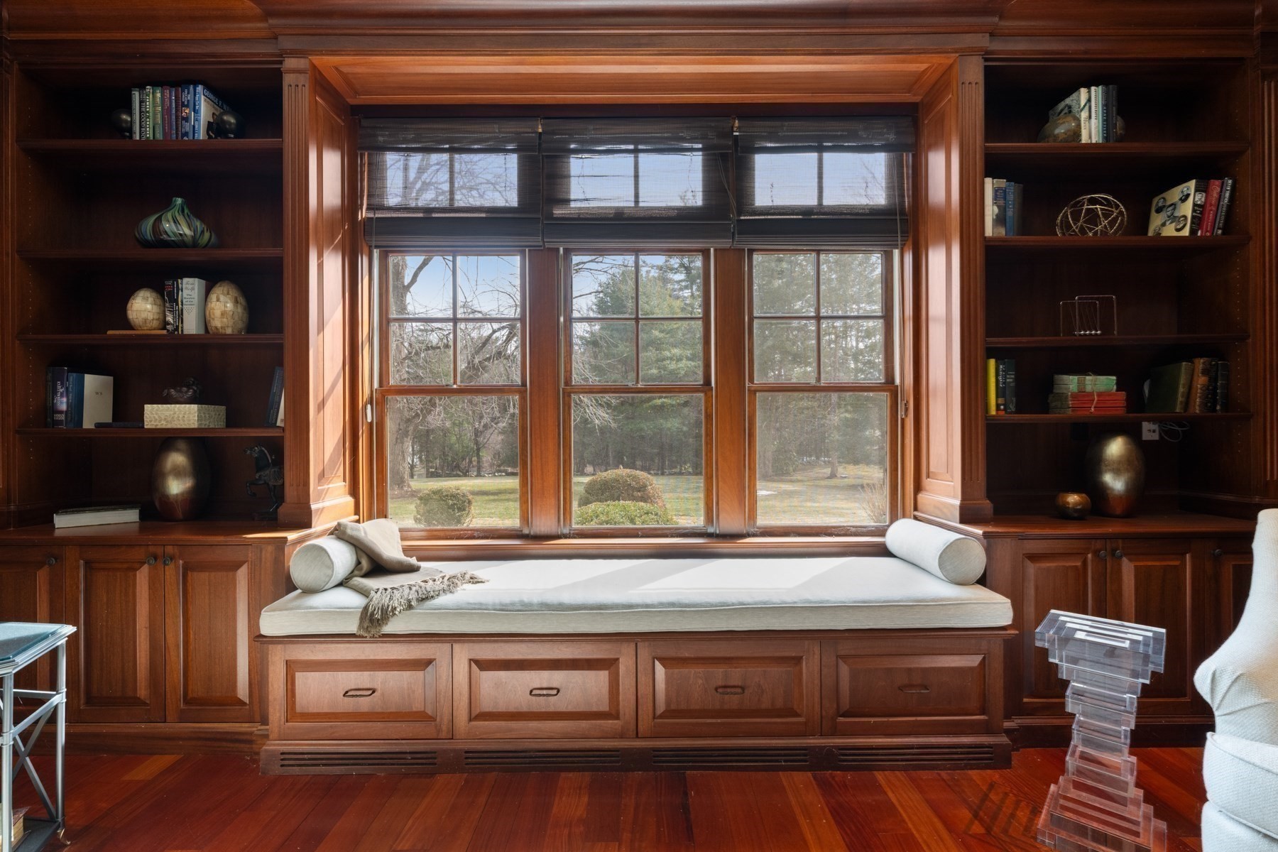 Built-in mahogany window seat beneath a large window, flanked by bookcases.