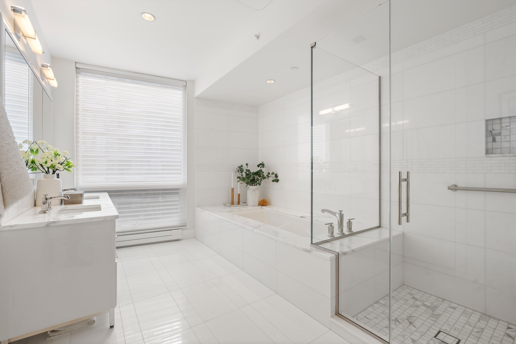 Modern white bathroom with a marble-trimmed tub and glass-enclosed shower.