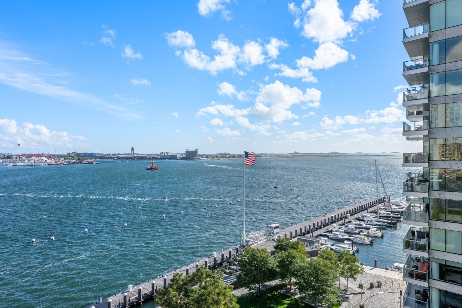 Boston Harbor view with boats, a marina, and glass balconies along the waterfront.