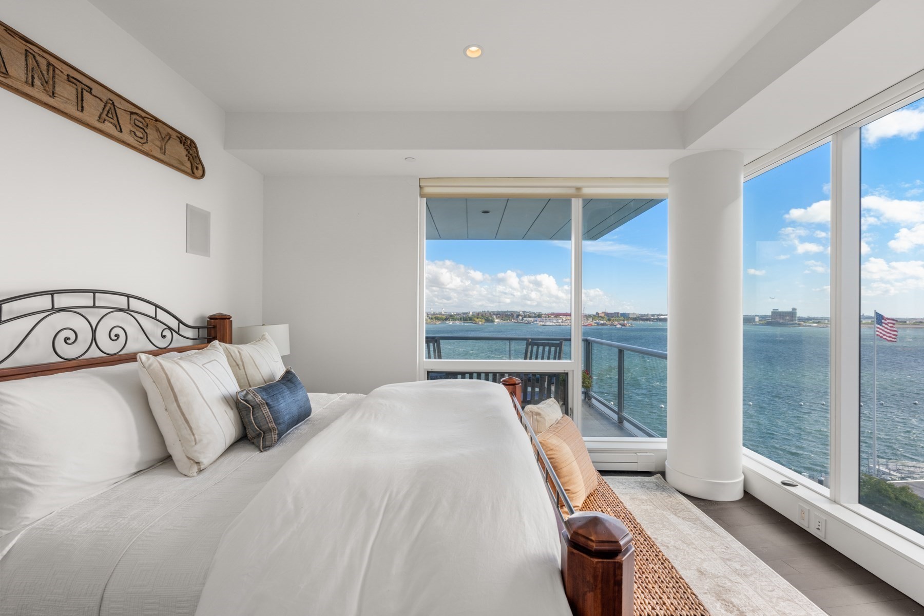 Bedroom with a harbor view through floor-to-ceiling windows and a balcony.