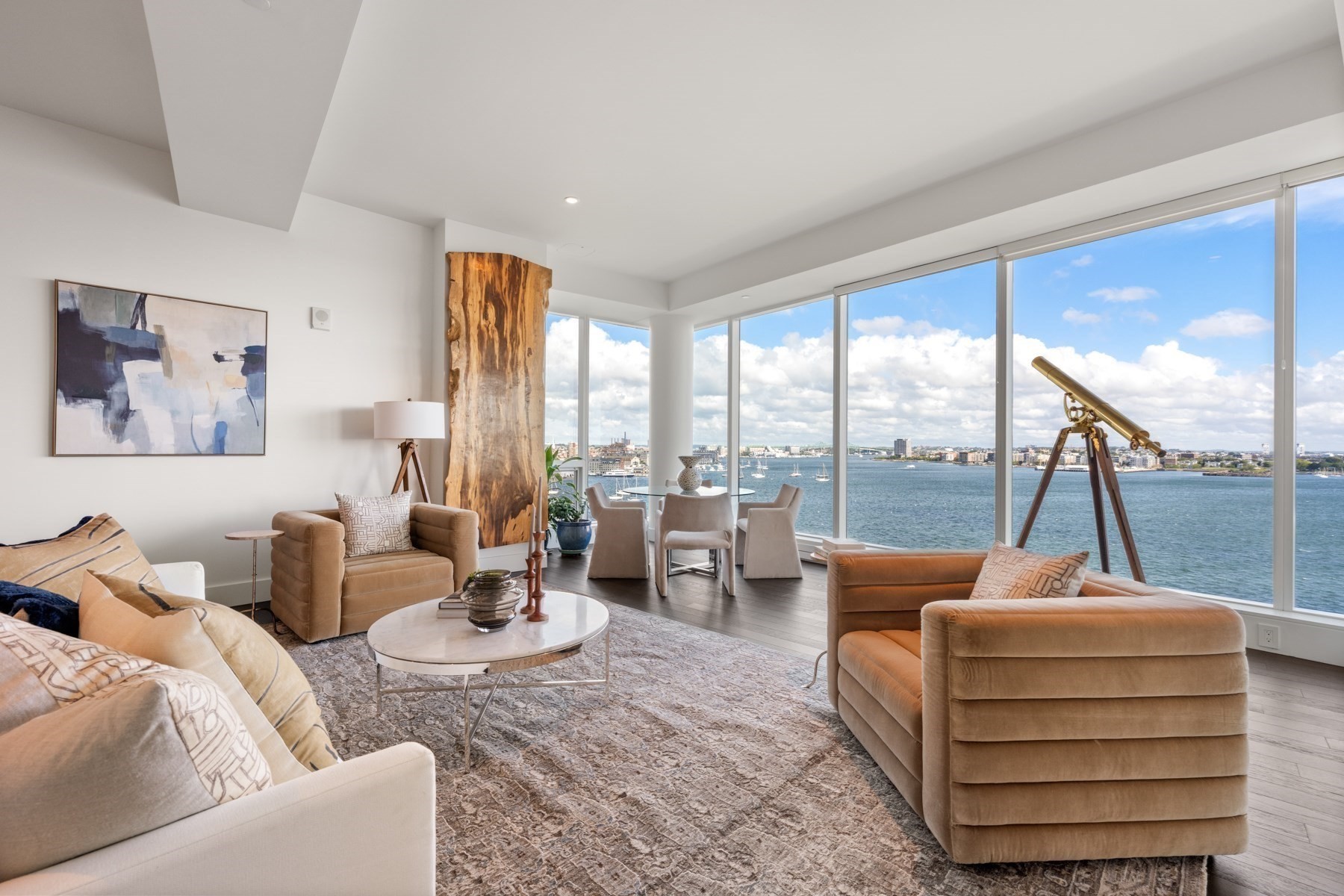 Furnished living room with panoramic harbor views, floor-to-ceiling windows, and a brass telescope.