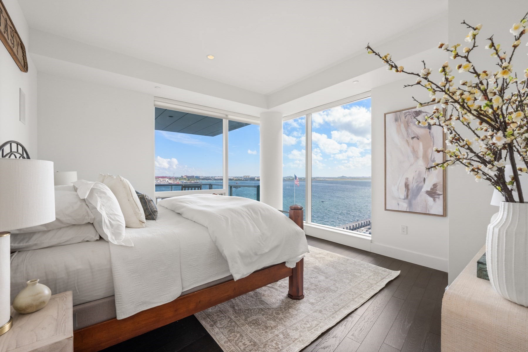 Staged bedroom with floor-to-ceiling windows overlooking Boston Harbor.