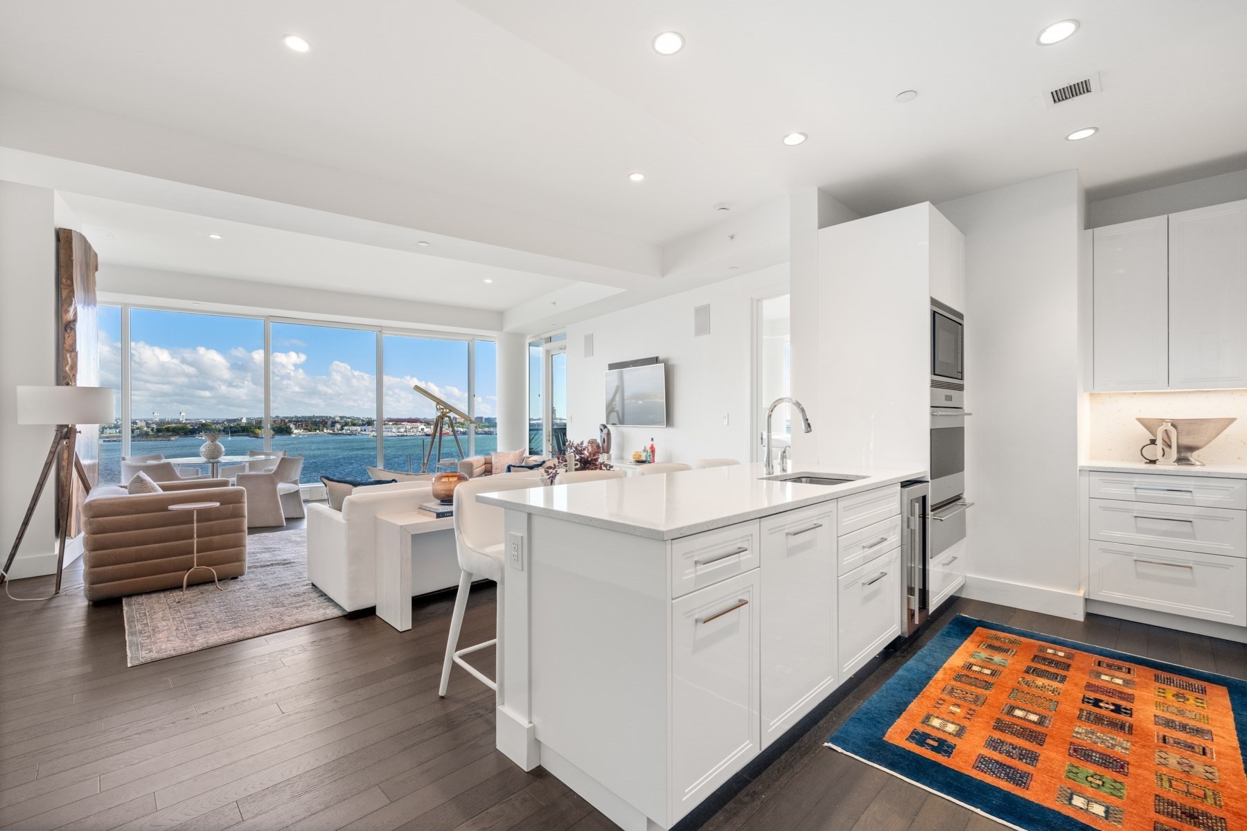 Open-plan kitchen and living room with a large island and floor-to-ceiling water views.