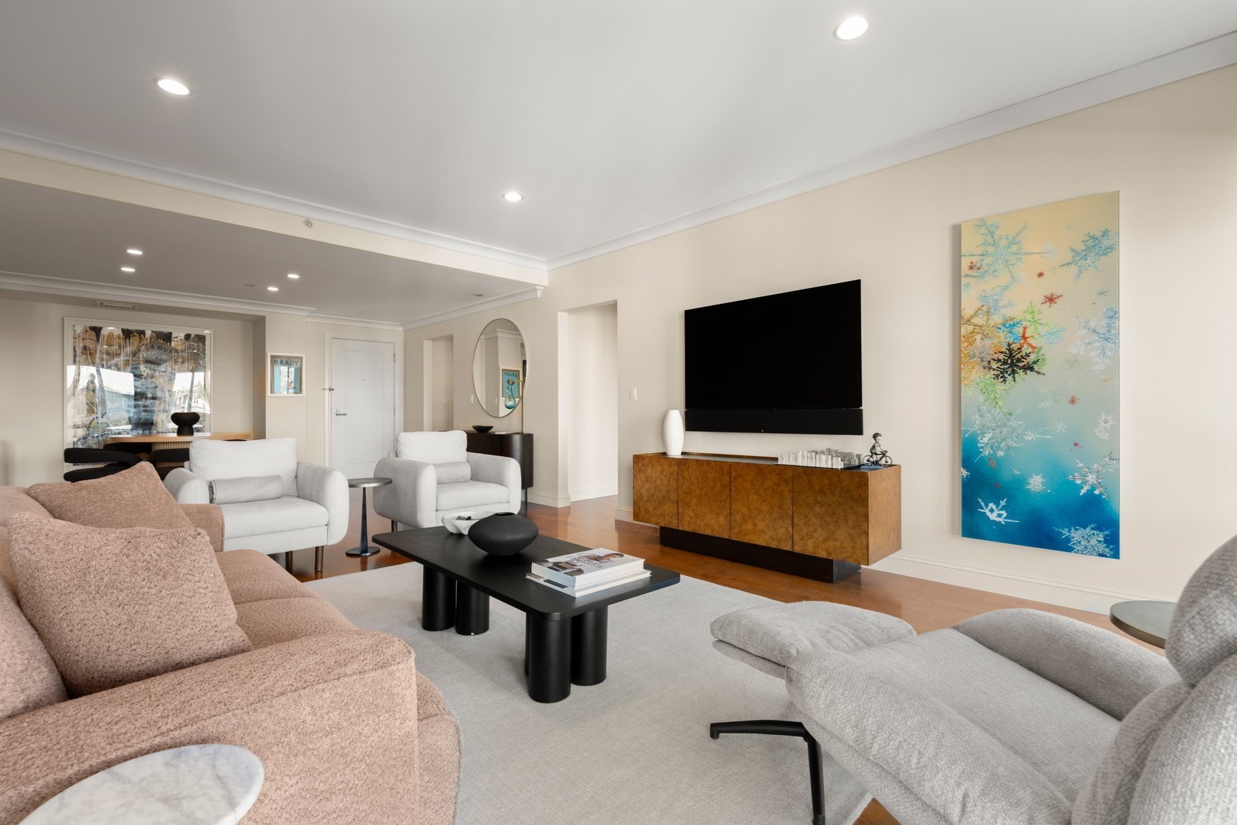 Living room with blush and gray sofas, a wall-mounted television, and colorful abstract artwork.