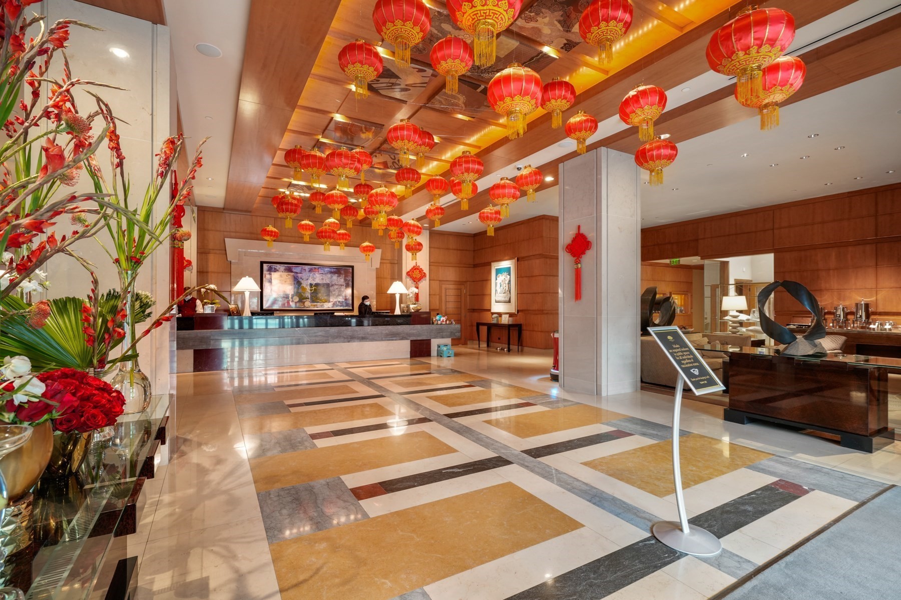 Building lobby with red hanging lanterns, a reception desk, and polished stone flooring.