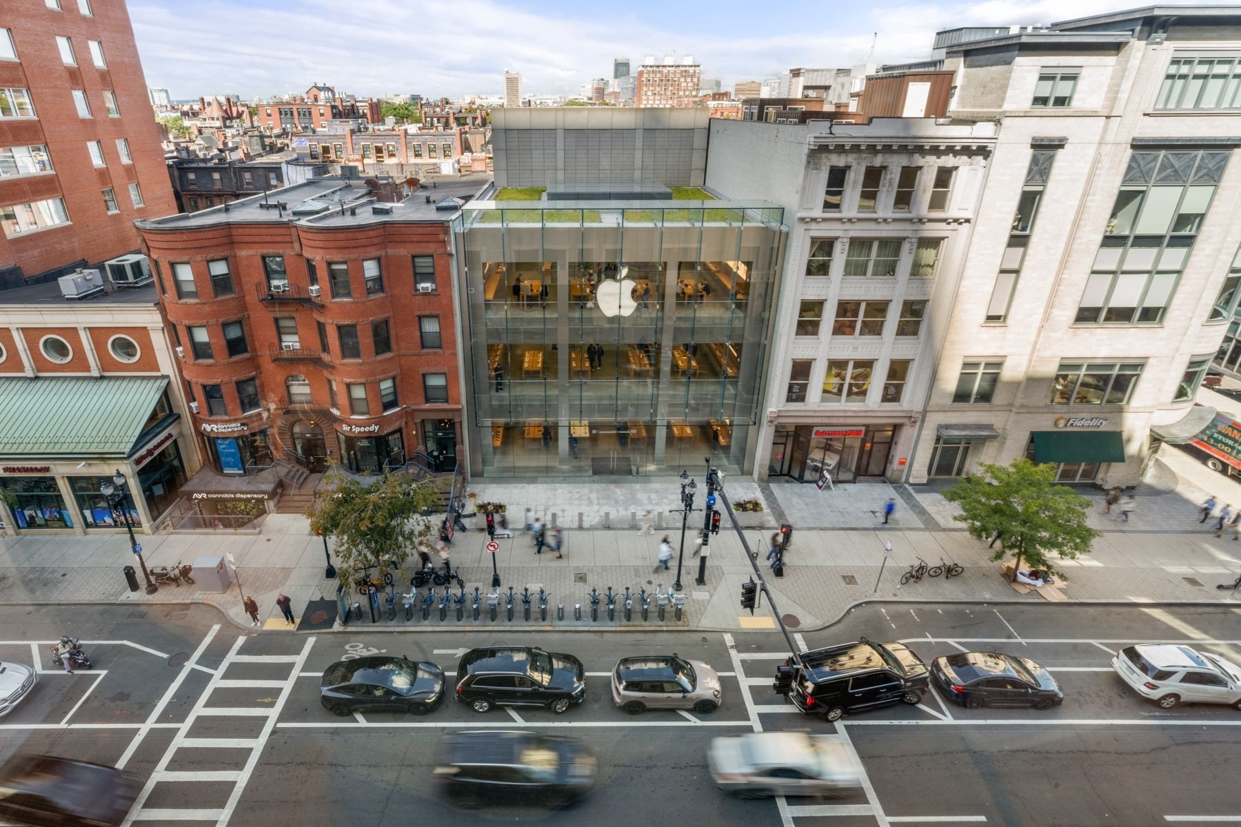 Panoramic view of Boylston Street, centered on the glass-fronted Apple Store and surrounding historic buildings.
