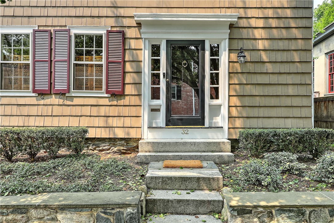 Home entrance with white trim, burgundy shutters, and stone steps leading to the front door.
