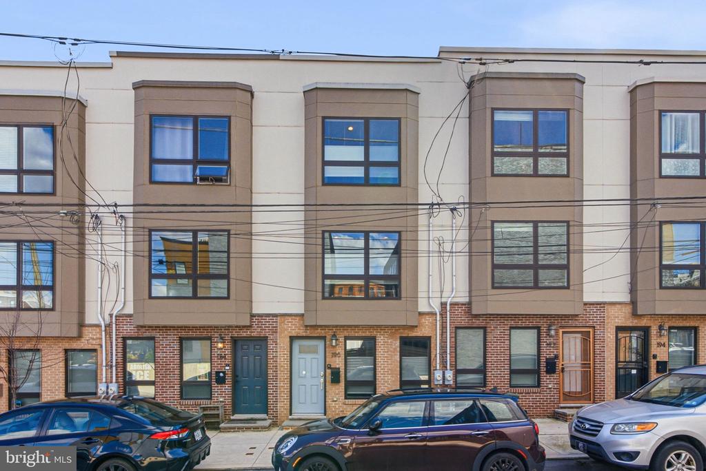 Attached townhouses with projecting bay windows and brick ground floors along a city street.