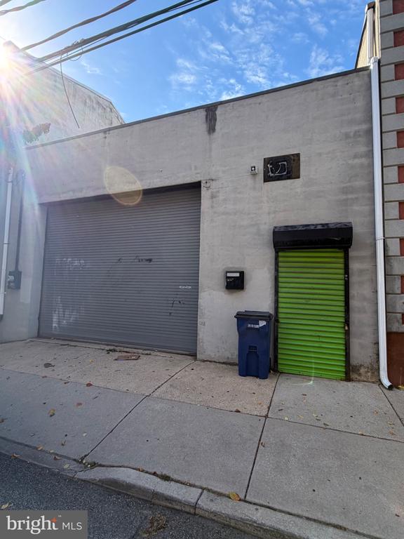 Concrete commercial building with a wide gray garage door and a bright green roll-up door.